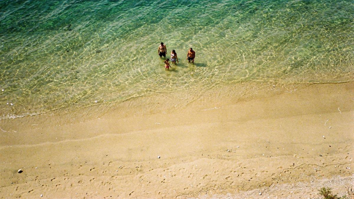 Shallow sandy shelf at Lara beach near Antalya, with a family standing knee-deep far from the shoreline